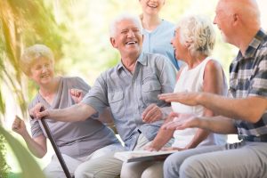 Group of seniors laugh and enjoy a moment while relaxing outside 