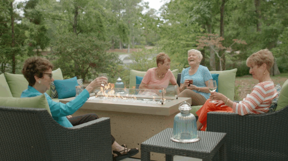 Elderly women drinking wine around a table outside