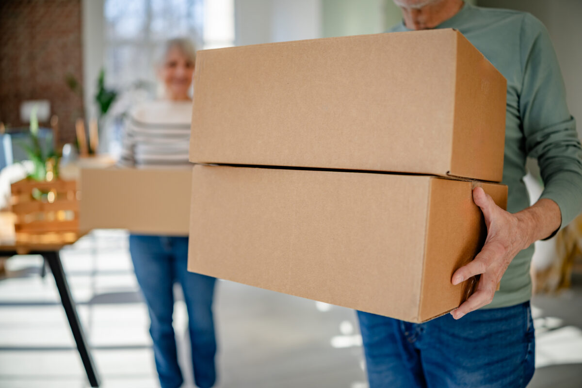 A senior couple holding moving boxes