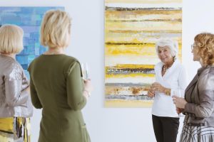 Group of mature women admire artwork at a museum