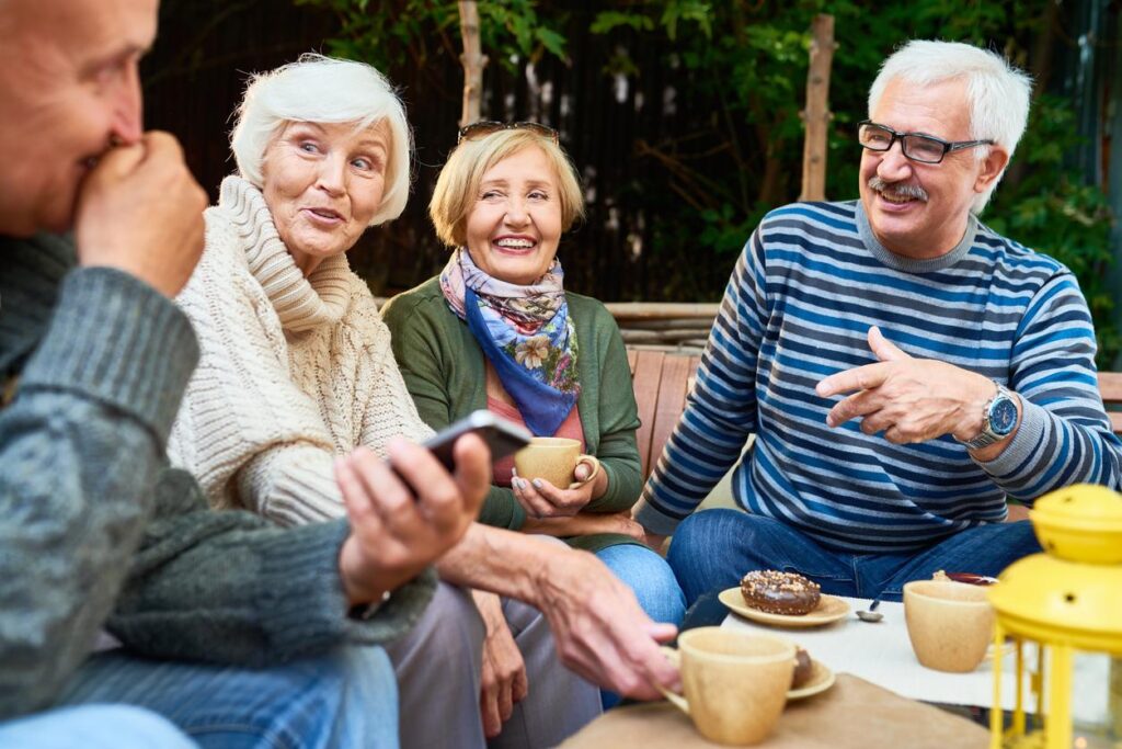 A group of mature adults enjoy coffee and donuts as they chat outside